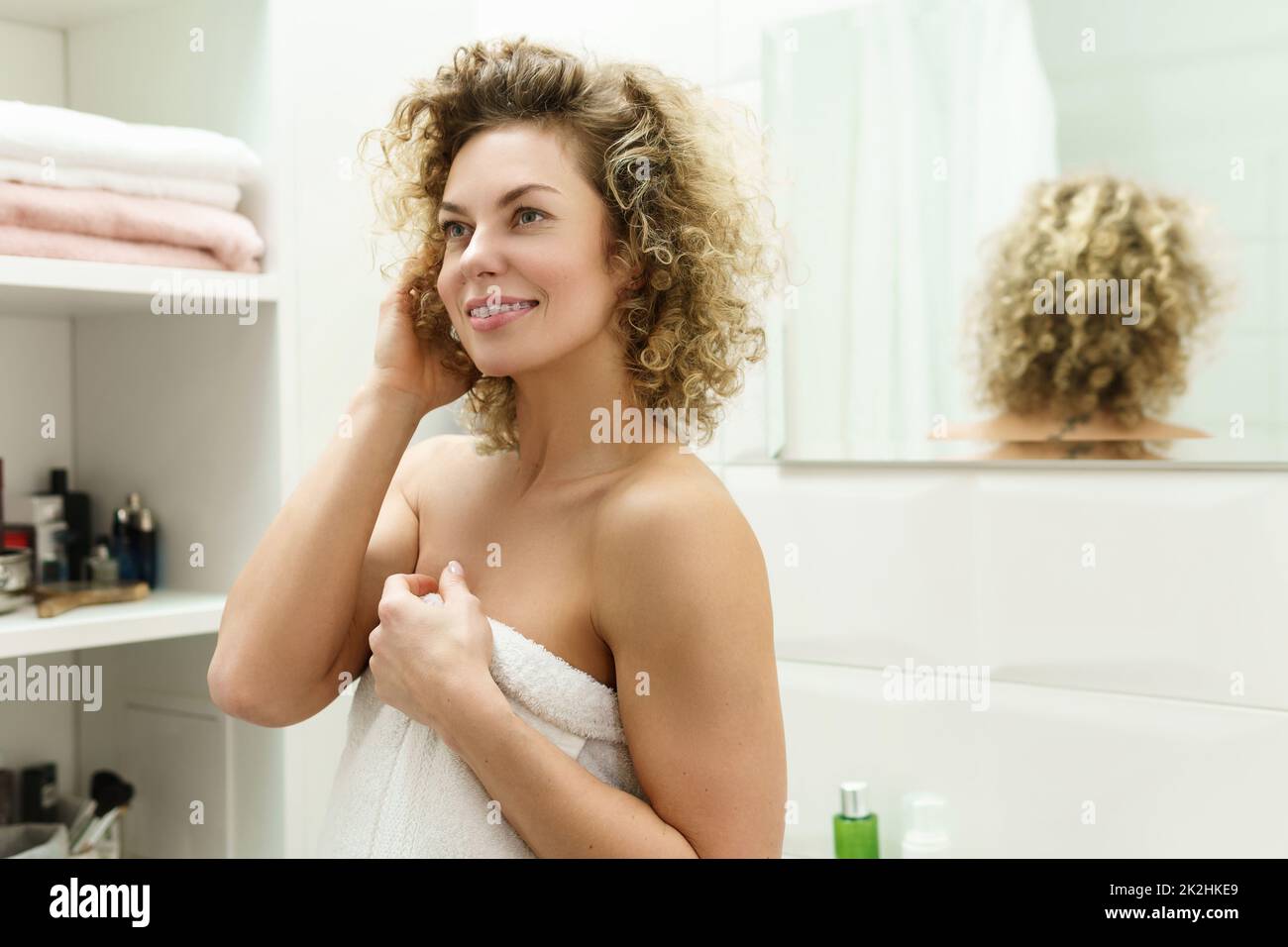 Wunderschöne Frau mit lockigem Haar nach einer Dusche im Badezimmer Stockfoto