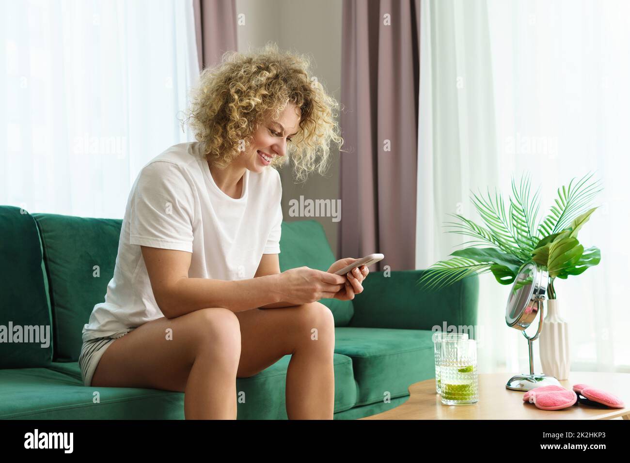 Junge und schöne Frau, die ihr Smartphone benutzt und sich zu Hause entspannt Stockfoto