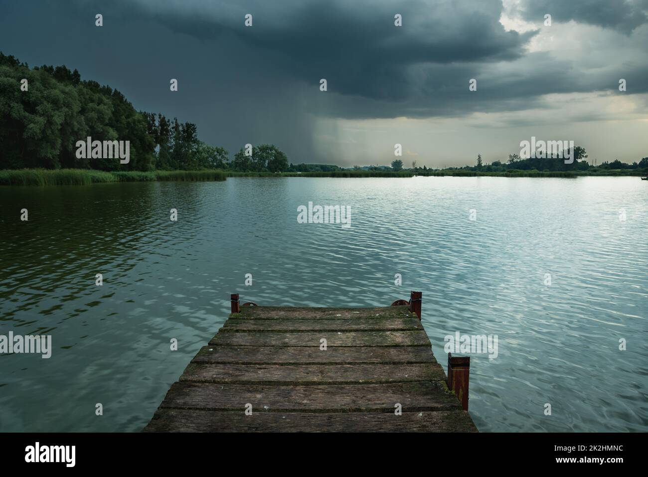 Hölzerner Pier zum See und eine Gewitterwolke Stockfoto