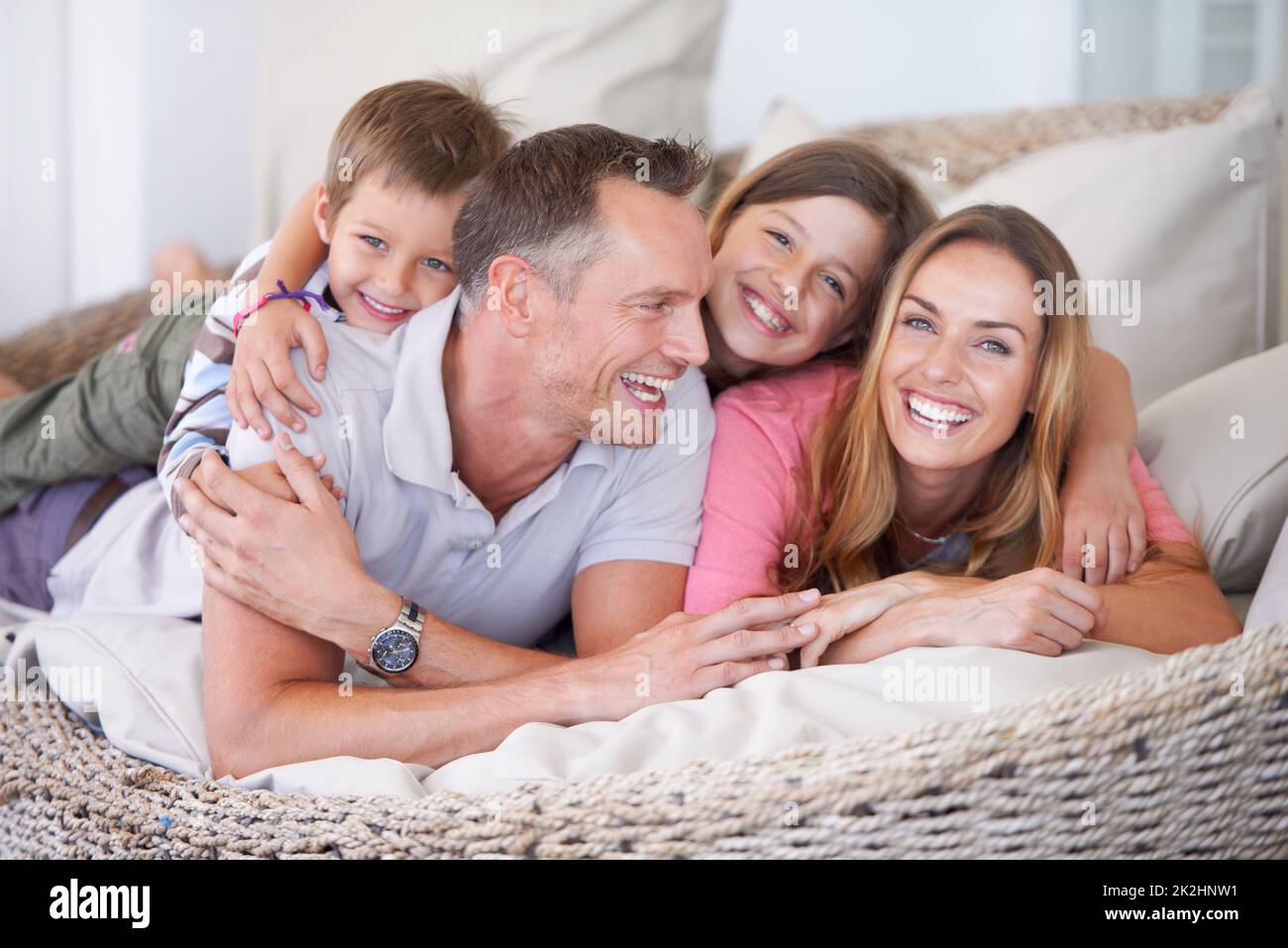 Kuscheln sich zusammen. Porträt einer glücklichen, jungen vierköpfigen Familie, die auf der Terrasse sitzt. Stockfoto