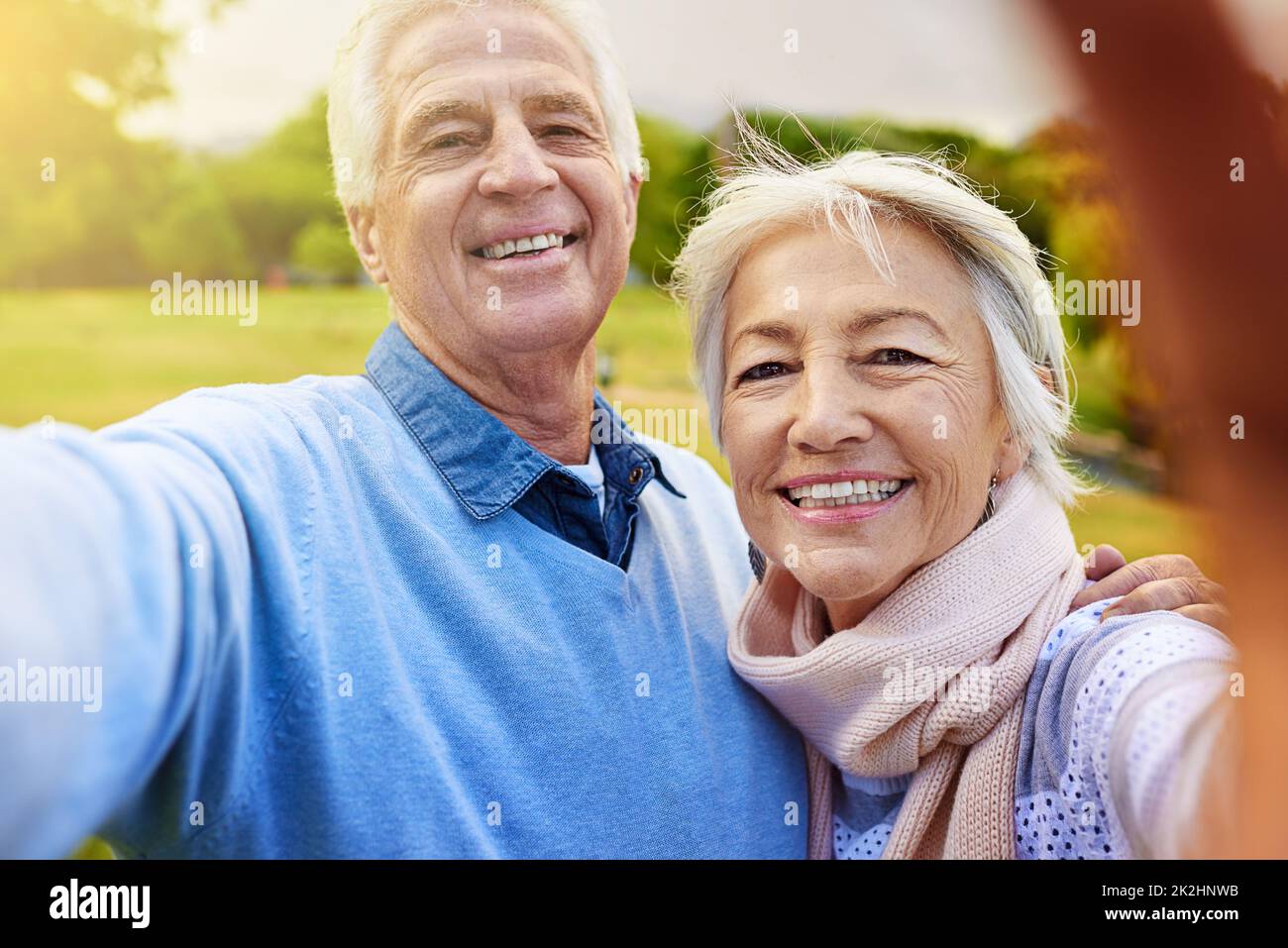 Lächeln Sie für die Kamera. Porträt eines älteren Paares, das zusammen in einem Park ein Foto gemacht hat. Stockfoto