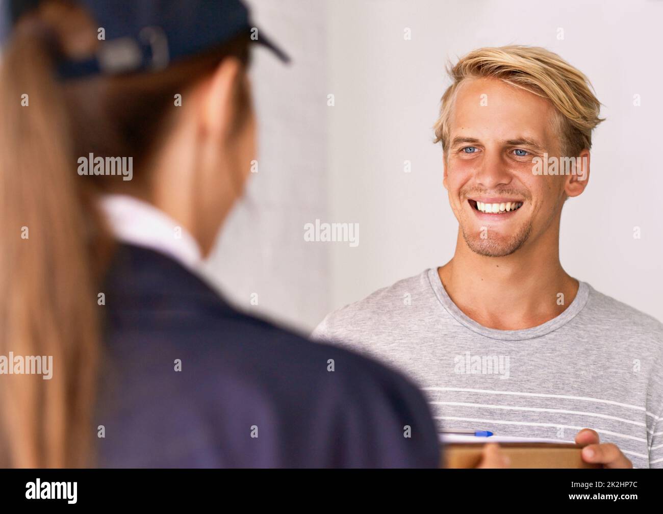 Ihre Service-Lieferung hinterlässt immer einen bleibenden Eindruck. Ein Kurier, der eine Lieferung an einen zufriedenen Kunden macht. Stockfoto