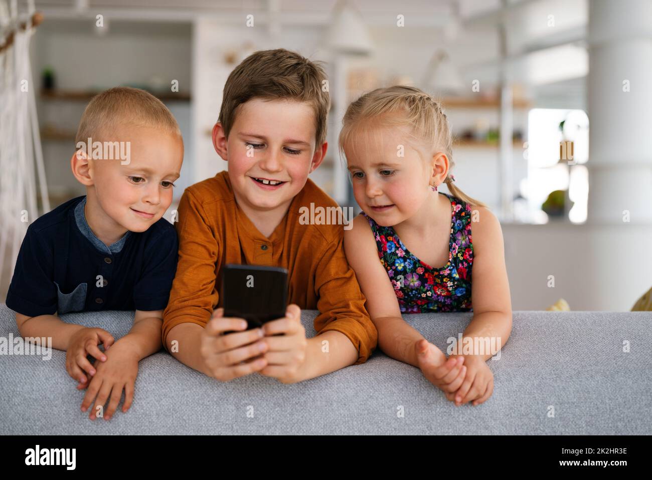 Kindheitstechnologie Kinder Smartphone Konzept. Glückliche kleine Kinder spielen auf dem Handy Stockfoto