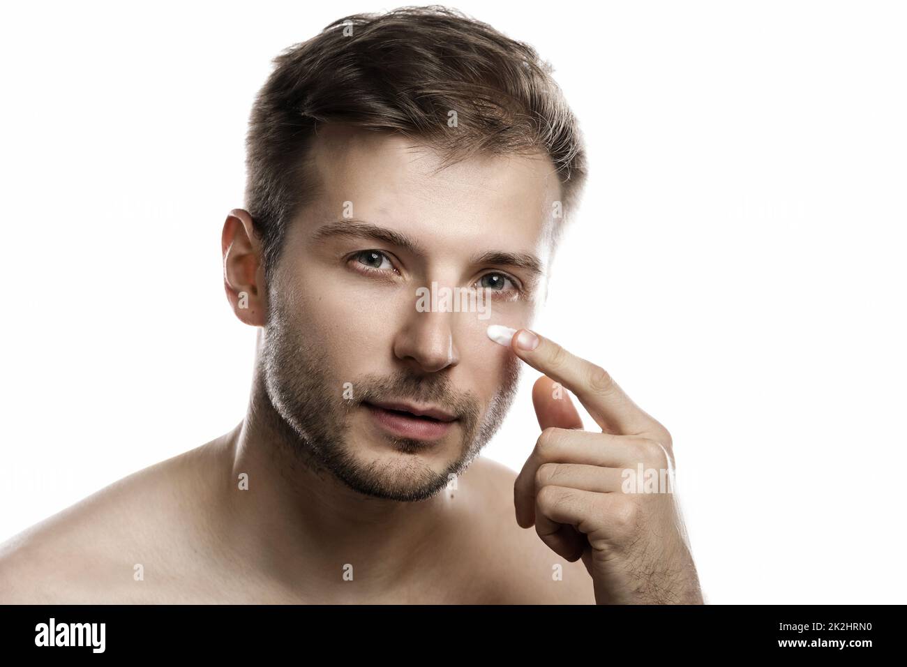 Schönheit für Männer. Der junge Mann wendet feuchtigkeitsspendende und Anti-Aging-Creme auf sein Gesicht an Stockfoto