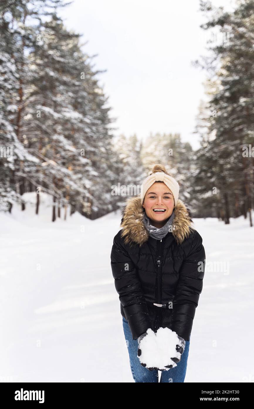 Eine junge Frau hielt während ihres Spaziergangs im Winterpark einen Schneehaufen in den Händen Stockfoto