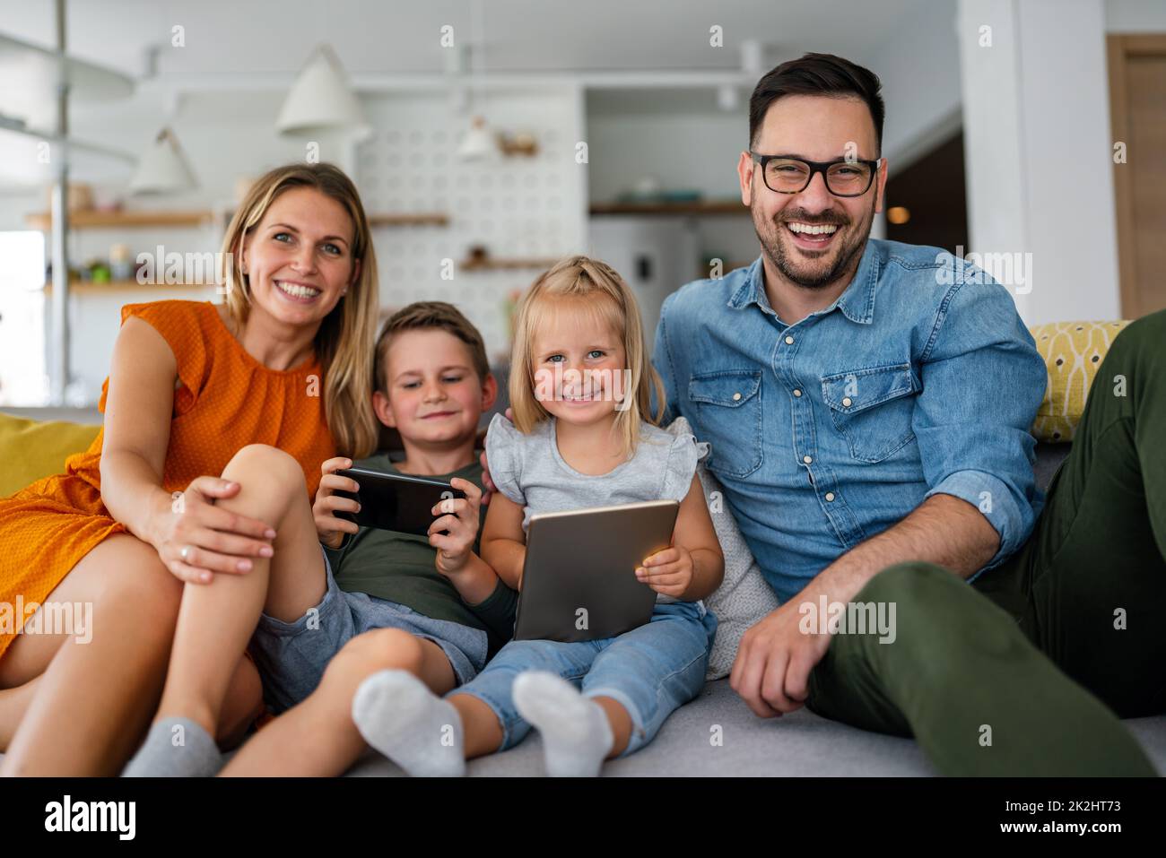Glückliche junge Familie, die Spaß zu Hause hat. Eltern mit Kindern, die ein Tablet benutzen Stockfoto
