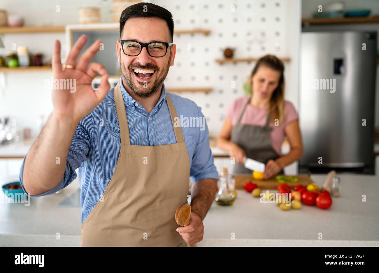 Porträt eines gutaussehenden glücklichen Mannes, der zu Hause kocht und in der Küche Essen zubereitet. Stockfoto