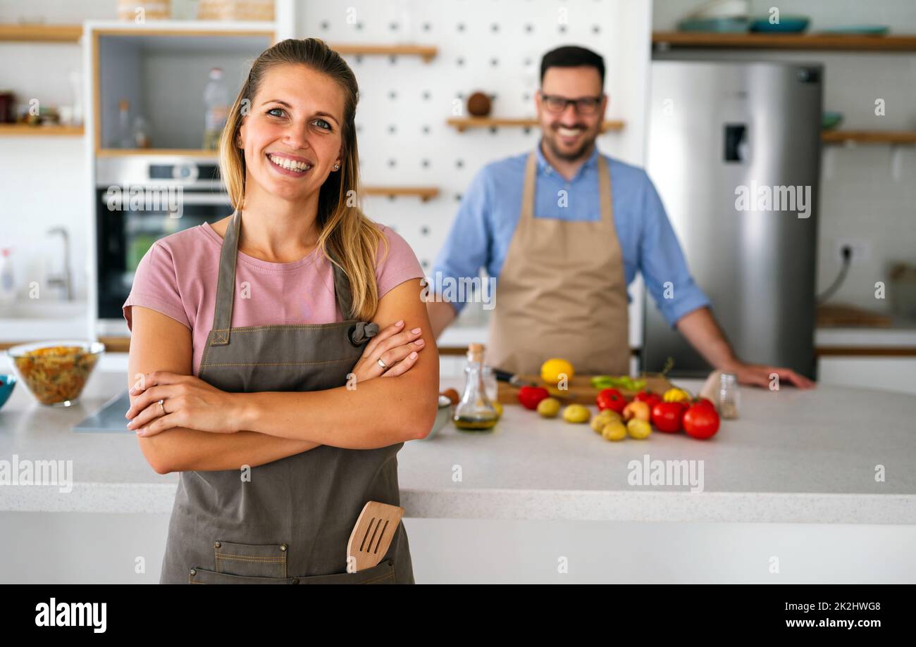 Das junge glückliche Paar genießt und bereitet gemeinsam gesunde Mahlzeiten in ihrer Küche zu Stockfoto