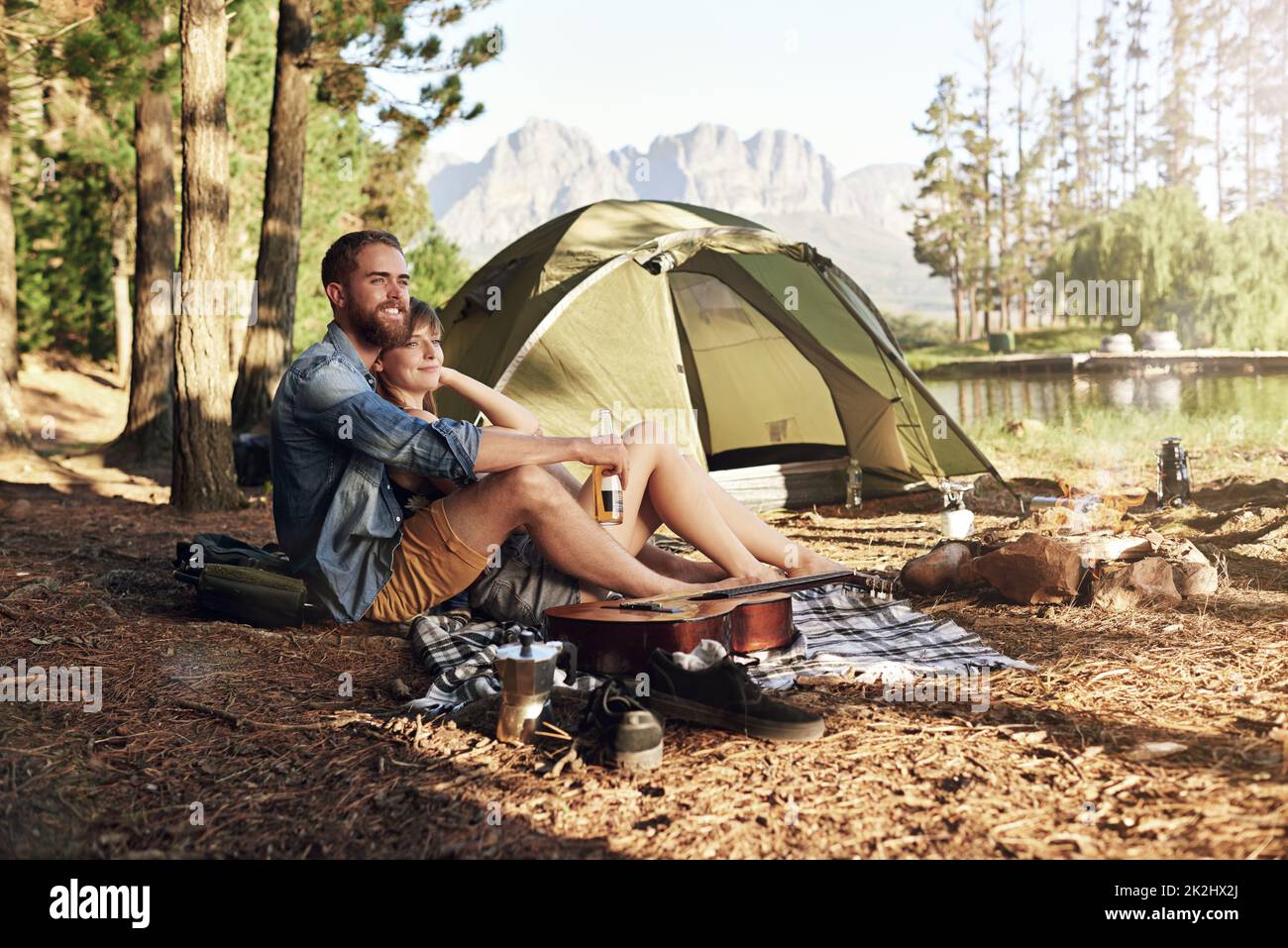 In den Wald. Aufnahme eines liebevollen jungen Paares, das auf ihrem Campingplatz sitzt. Stockfoto