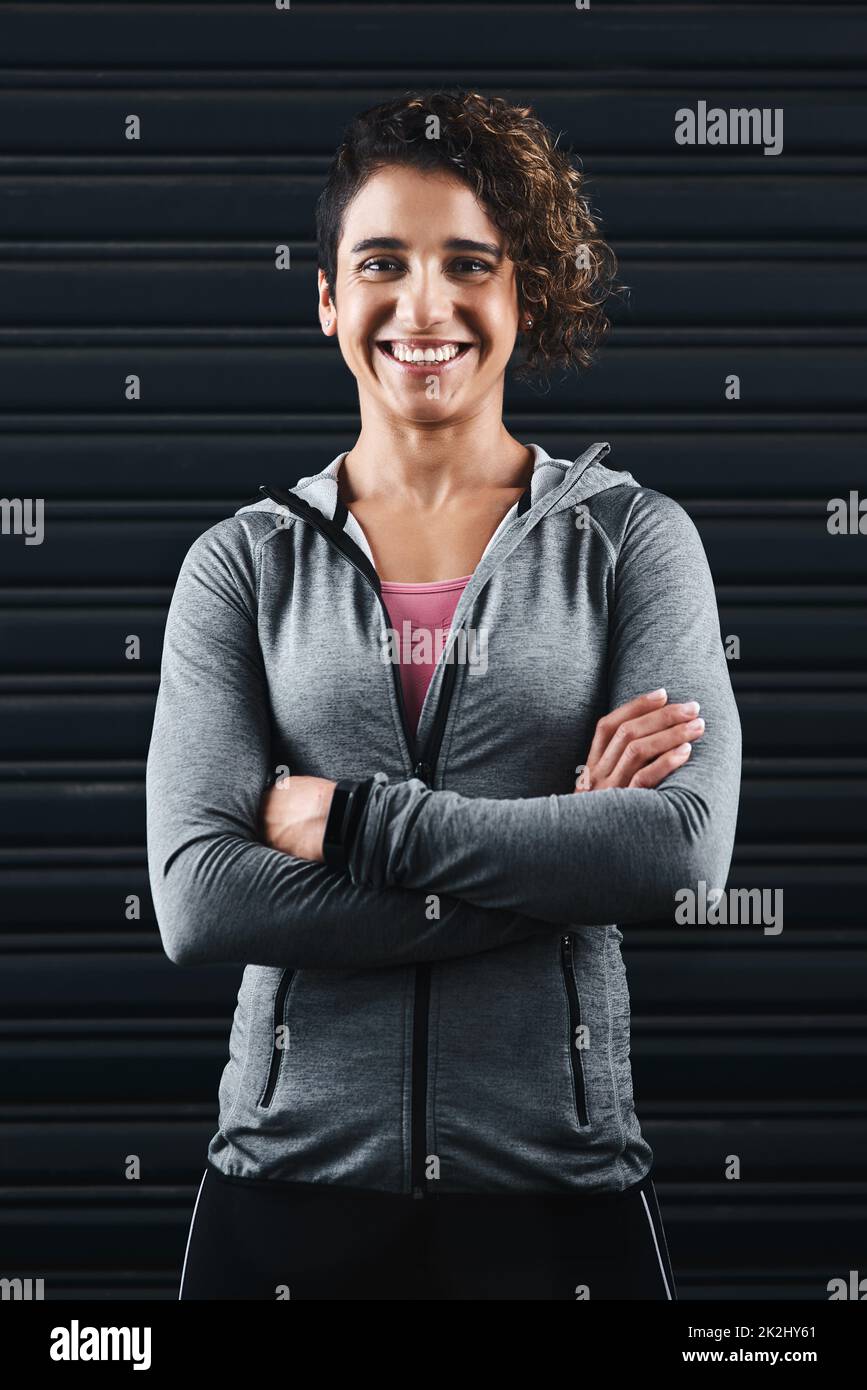 Gesund zu sein macht mich glücklich. Verkürztes Porträt einer attraktiven jungen Frau, die vor dem Training in ihrer Trainingskleidung vor schwarzem Hintergrund steht. Stockfoto