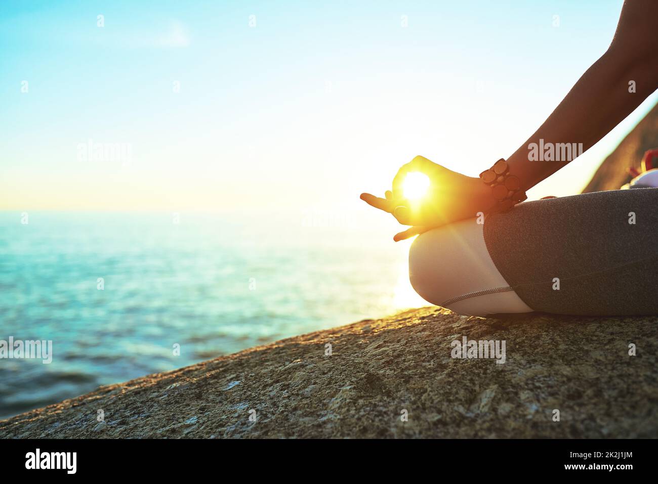 Die perfekte Umgebung für perfekte Ruhe. Eine ausgeschnittene Aufnahme einer Frau, die am Strand die Lotushaltung übt. Stockfoto