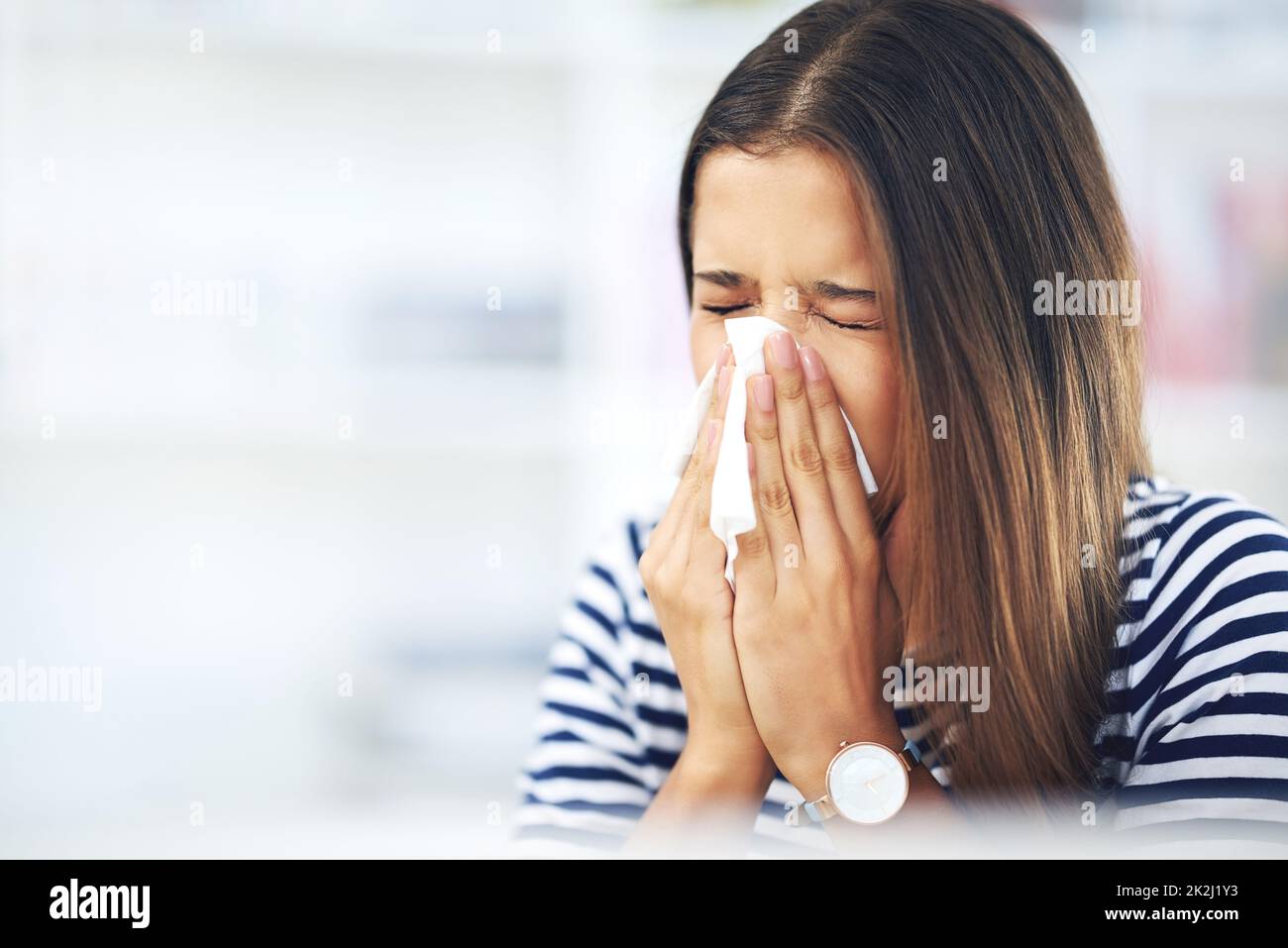 Seine Allergie-Saison wieder. Aufnahme einer jungen Frau mit Allergien, die zu Hause in ein Gewebe niest. Stockfoto