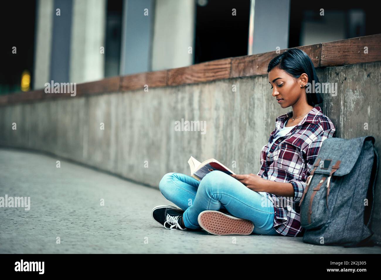 Mein Lieblingsort zum Studieren. Aufnahme einer jungen Studentin, die draußen auf dem Campus ein Buch liest. Stockfoto