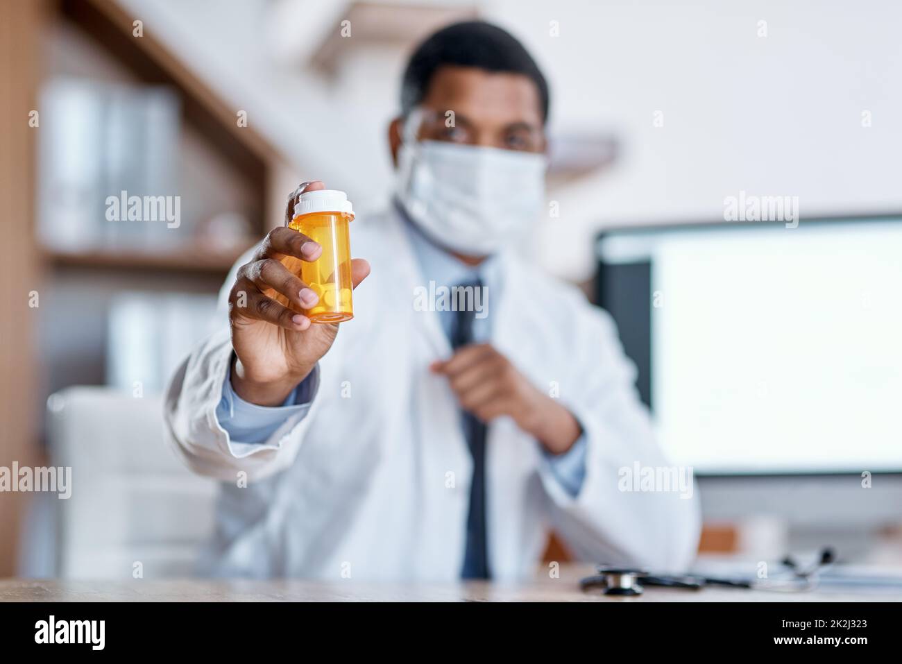 Dies wird Ihren Zustand heilen. Nahaufnahme eines nicht erkennbaren Arztes, der eine Flasche Pillen in seinem Büro hält. Stockfoto