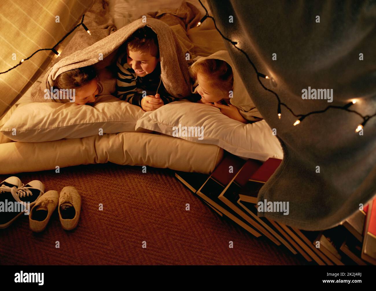Shh... oder Mama wird uns ins Bett bringen. Drei kleine Kinder spielen zusammen in einem Zelt. Stockfoto