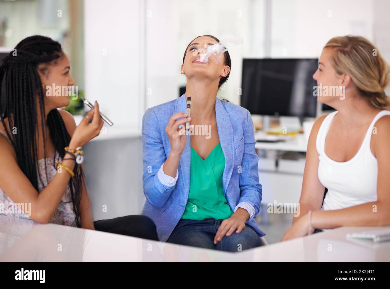 Sozial rauchen ohne Stigma. Geschäftsfrauen rauchen elektronische Zigaretten im Büro. Stockfoto