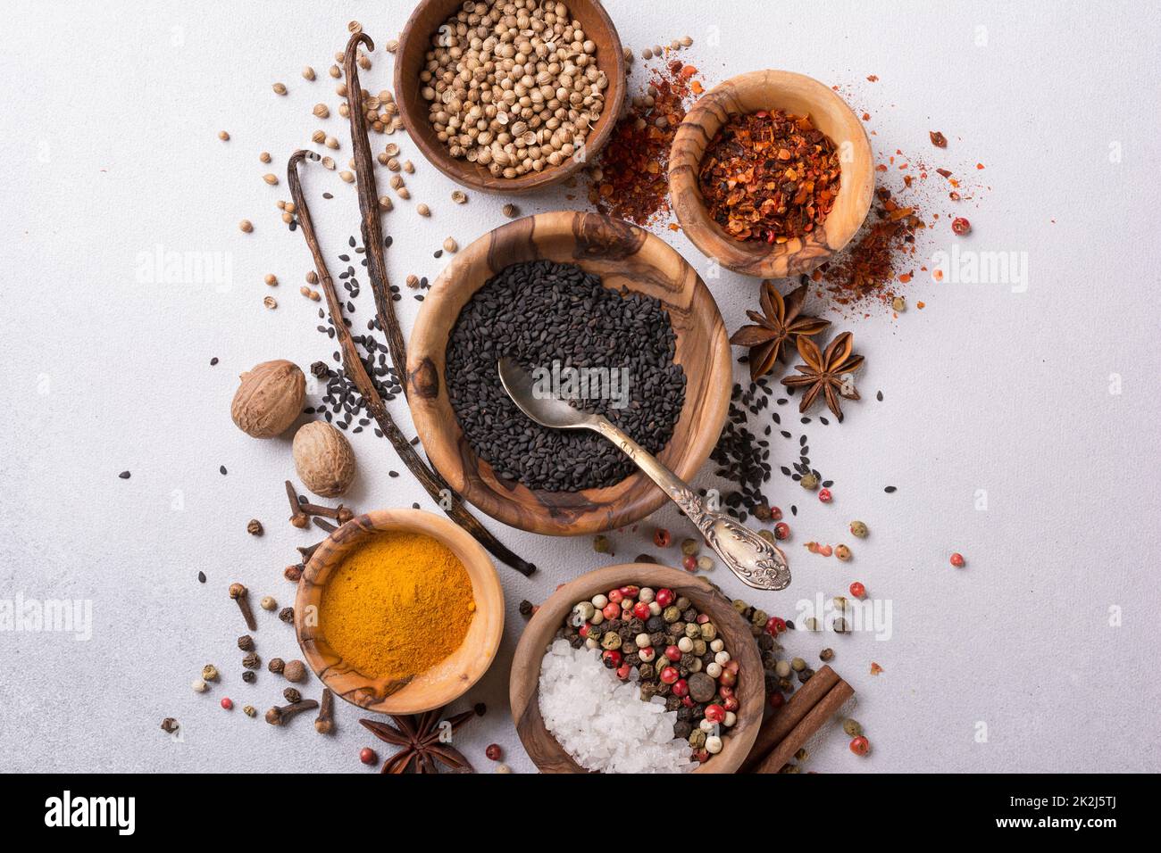 Draufsicht auf Mix helle Gewürze oder Gewürze in kleinen Holzschüsseln als Zutat für gesunde Lebensmittel auf grauem Beton-Hintergrund Stockfoto
