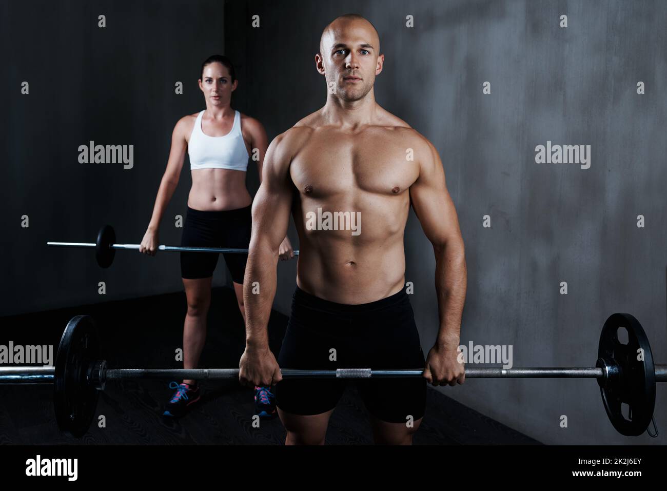 Training, um fit zu werden. Kurzer Schuss eines Mannes und einer Frau, die mit den Langhanteln arbeiten. Stockfoto