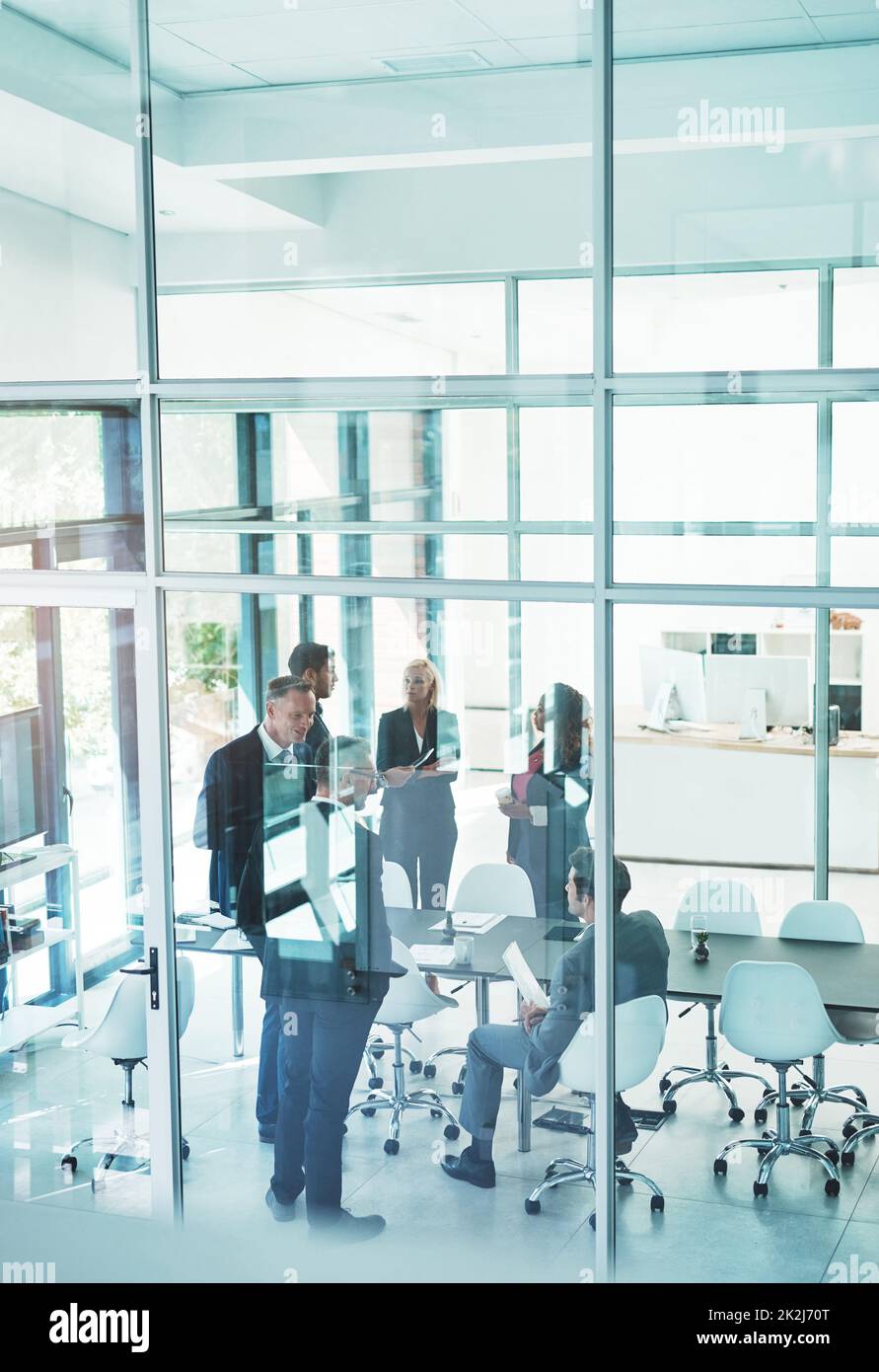 Es sieht so aus, als würden ihre Sitzungen unterbrochen. In voller Länge eine Gruppe von Geschäftsleuten, die sich im Sitzungssaal treffen. Stockfoto