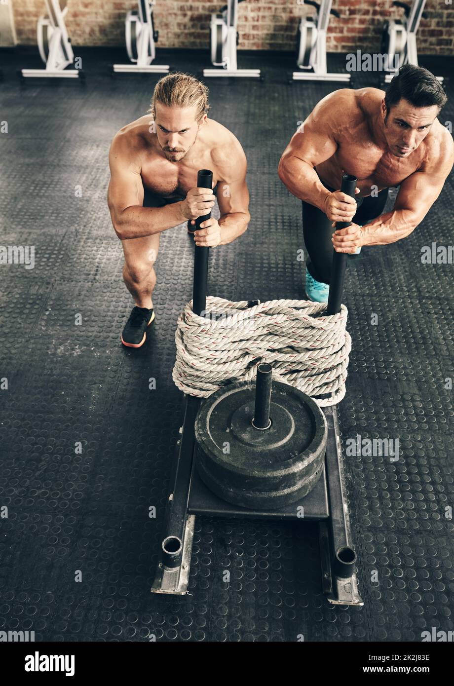 Zusammen ist das noch einfacher. Aufnahme von zwei fitten und entschlossenen jungen Männern, die Gewichte zum gemeinsamen Training in einem Fitnessstudio nutzen. Stockfoto