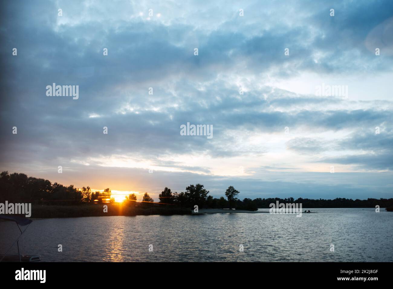 Blauer Sonnenuntergang auf dem Fluss mit Silhouetten Stockfoto