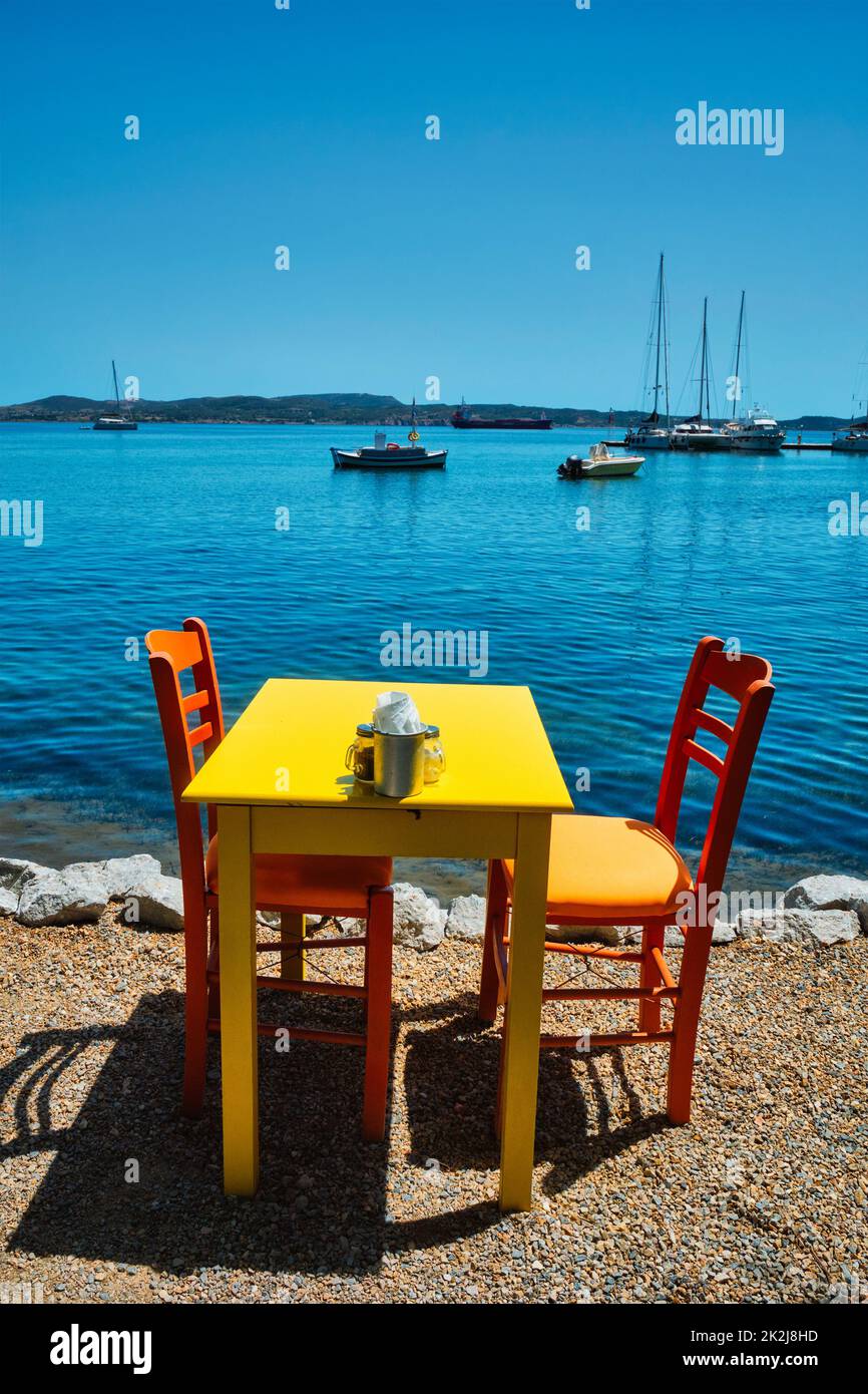 Café Tableon Strand in Adamantas Stadt auf Milos Insel mit Ägäis mit Booten im Hintergrund Stockfoto