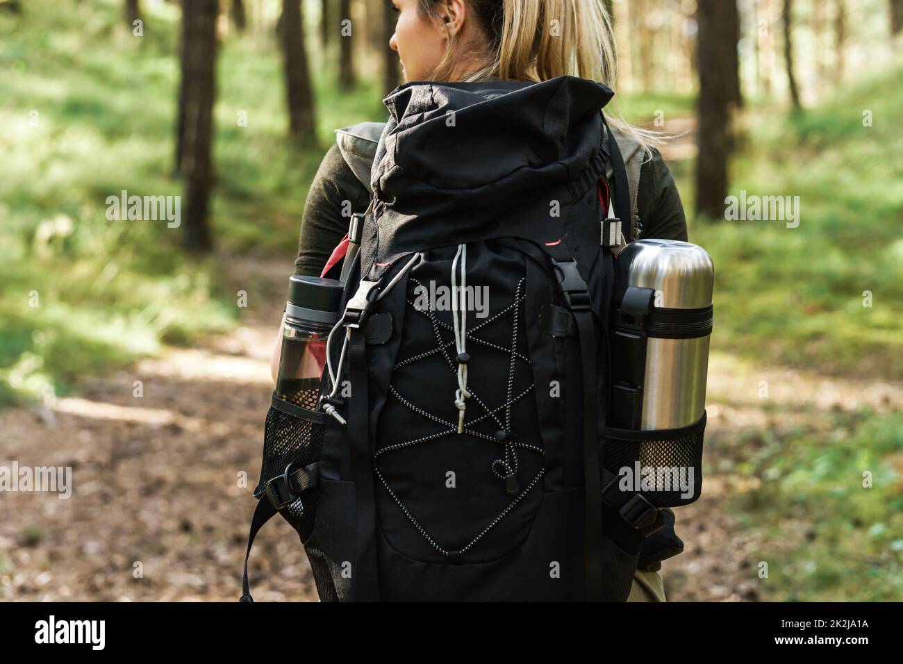 Wanderweibchen mit großem Rucksack im grünen Wald Stockfoto