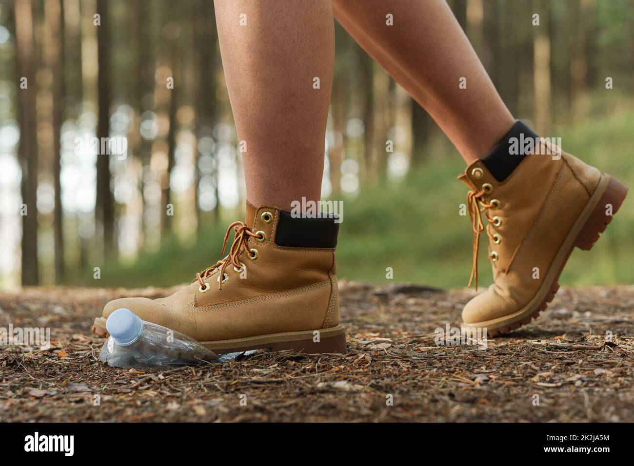 Gelbe Stiefel und Plastikflasche in einem Wald Stockfoto