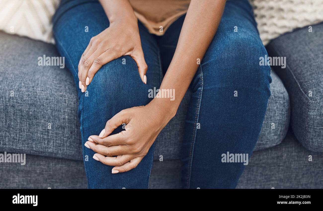 Schwarze Frau, Hände- und Knieschmerzen bei Personen auf dem Sofa im Wohnzimmer oder in der Lounge im Wohnzimmer. Zoom auf Gesundheit, Wellness oder medizinische Chirurgie Stockfoto