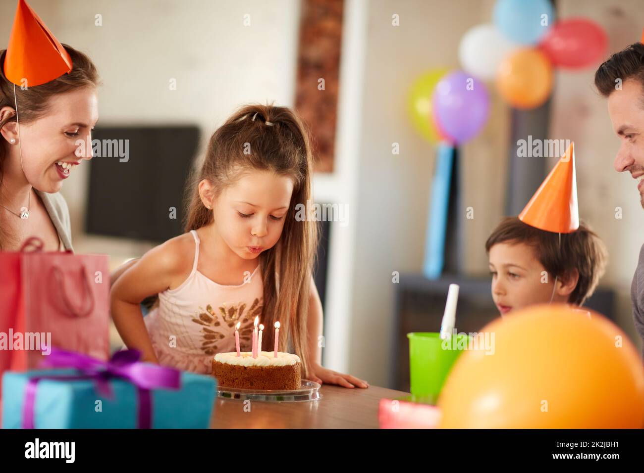 Kerzen blasen, während Sie sich wünschen. Eine kurze Aufnahme einer Familie, die zu Hause Geburtstag feiert. Stockfoto