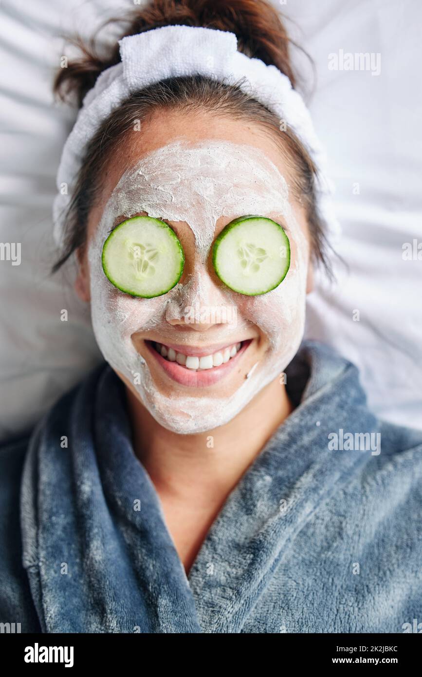 Zu Hause Spa-Tag. Aufnahme einer jungen Frau, die sich mit einer Gesichtsbehandlung im Gesicht legt. Stockfoto