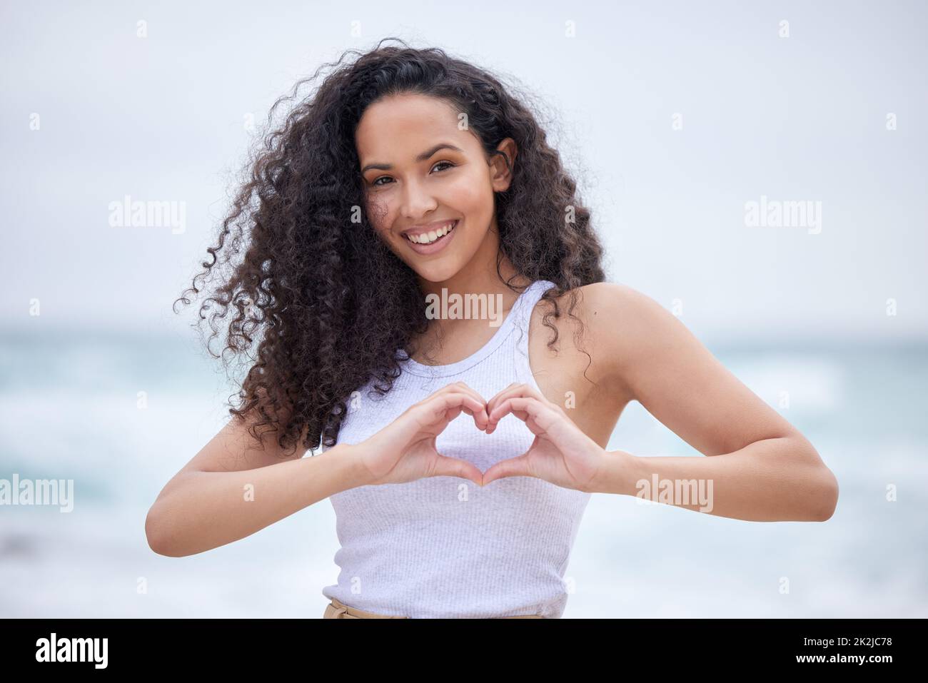 Liebe dich vor allem anderen. Aufnahme einer jungen Frau, die mit ihren Händen am Strand eine Herzbewegung macht. Stockfoto