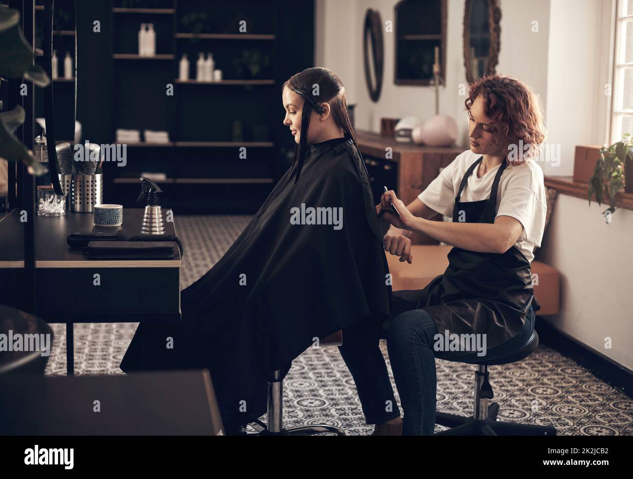 Sie macht immer einen guten Job mit meinen Haaren. Aufnahme eines Friseursalons, der einem Kunden in einem Salon die Haare schneidet. Stockfoto