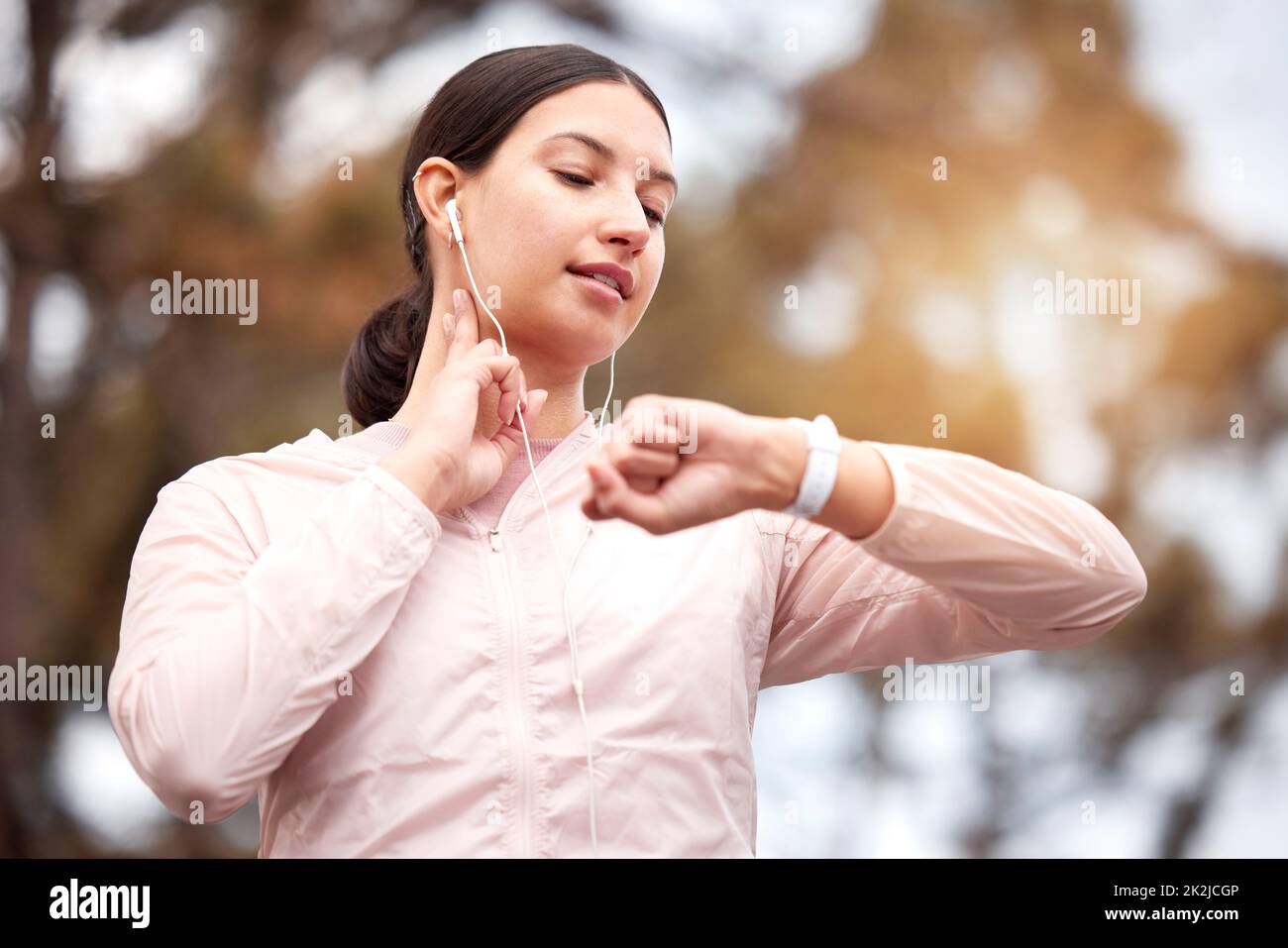 Aufrechterhaltung eines gesunden Lebensstils. Aufnahme einer jungen Frau, die ihren Puls während des Trainings in der Natur überprüft. Stockfoto