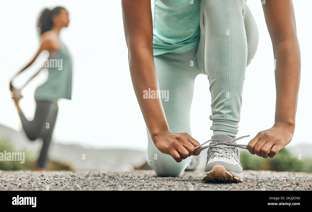 Laufen ist meine Therapie. Aufnahme einer nicht erkennbaren Person, die ihre Schnürsenkel vor einem Lauf festbindet. Stockfoto