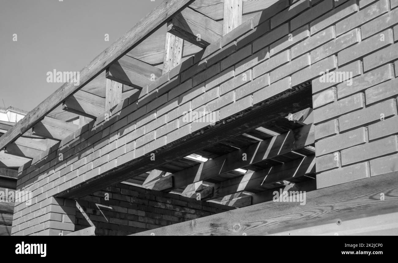 Schwarzweißfoto, ein im Bau befindliches Privatwohngebäude mit einer Holzrahmendachkonstruktion. Unbearbeitetes Ziegelgebäude im Bau, Nahaufnahme Stockfoto