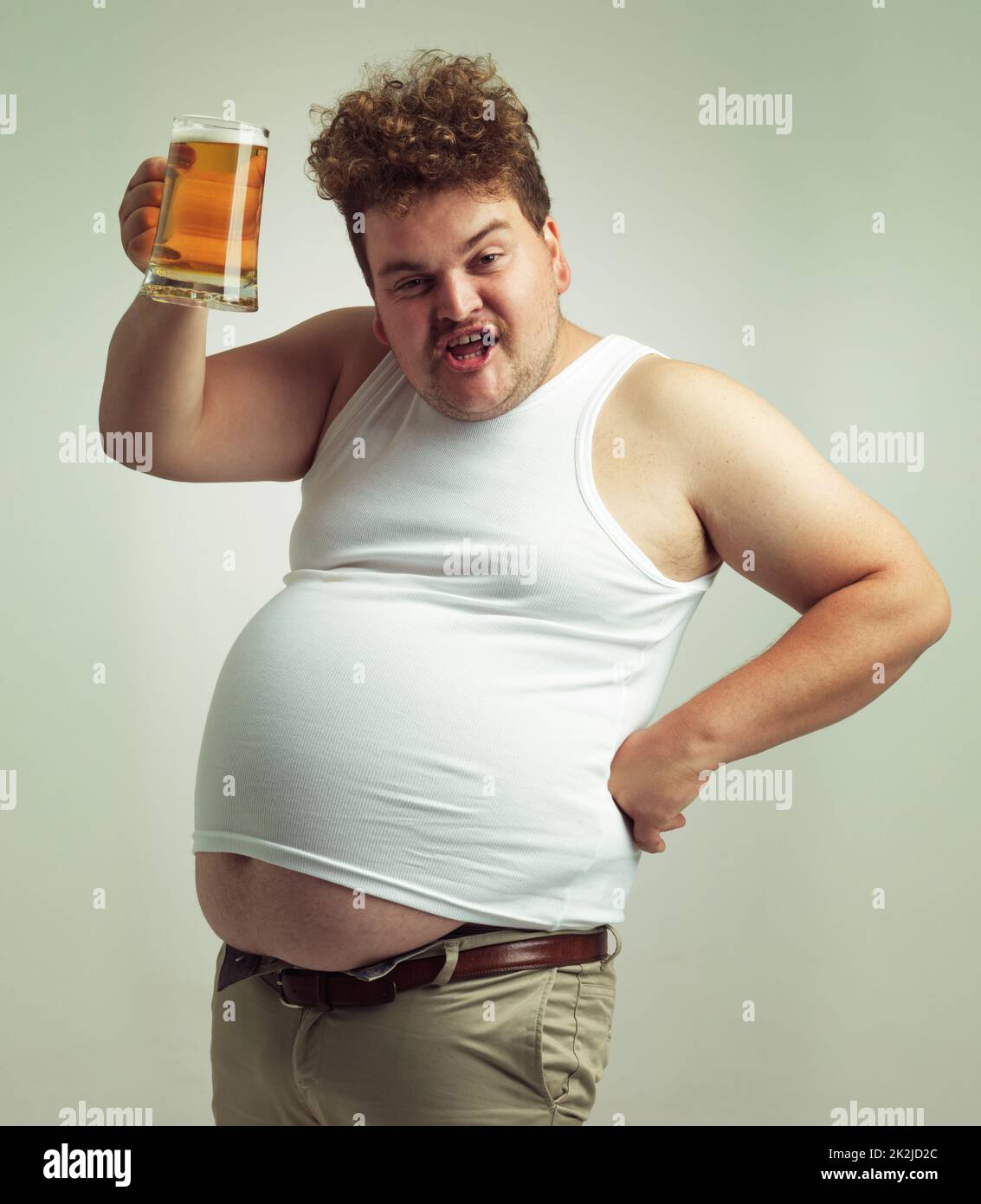 Prost. Aufnahme eines übergewichtigen Mannes, der sein Bier zum Anstoßen anhebt. Stockfoto