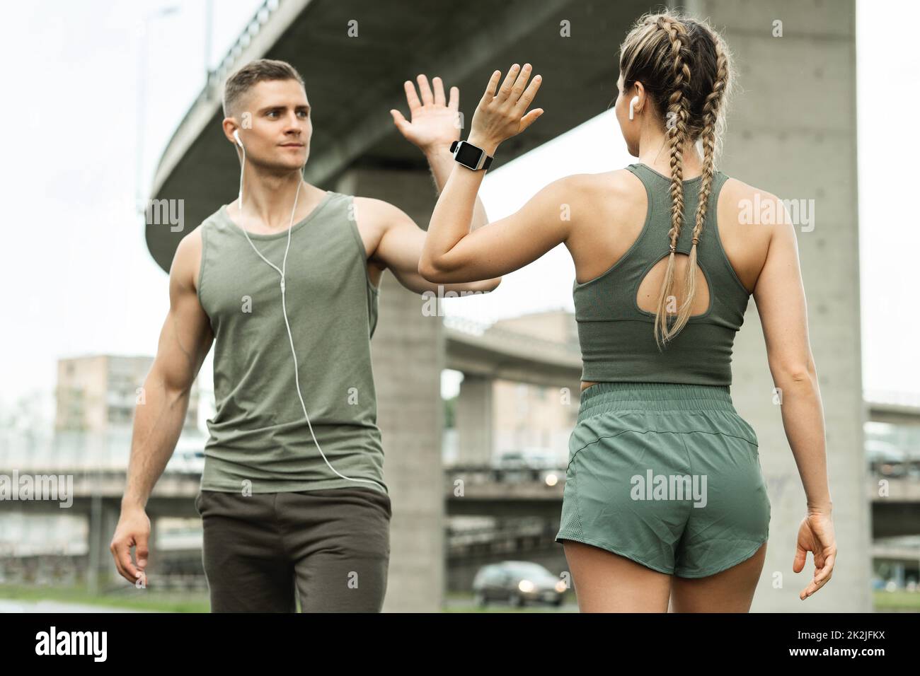 Zwei athletische Menschen begrüßen sich beim Jogging-Workout mit hohen fünf Gesten Stockfoto