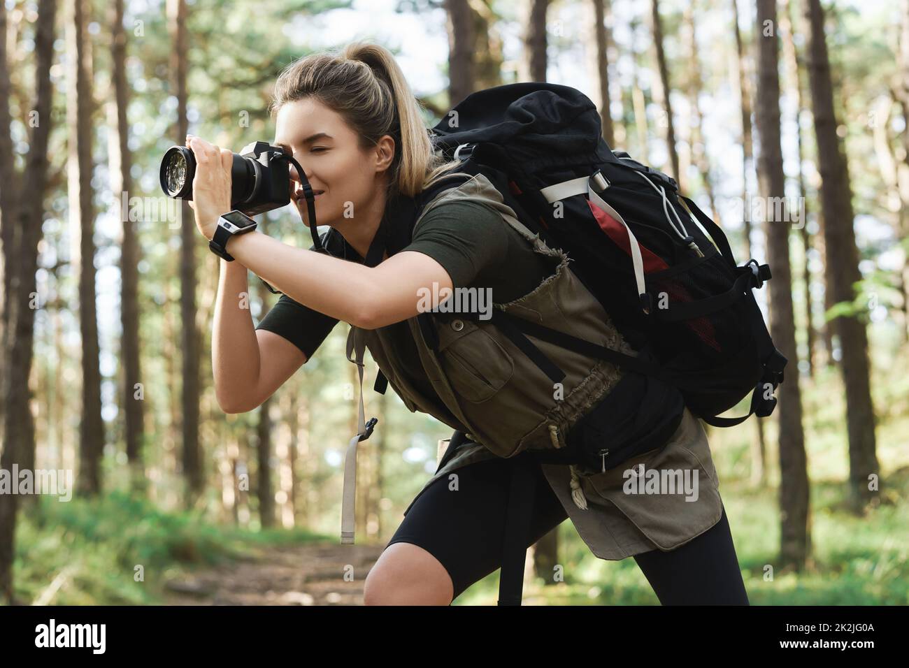 Wanderer fotografiert mit einer modernen spiegellosen Kamera im grünen Wald Stockfoto