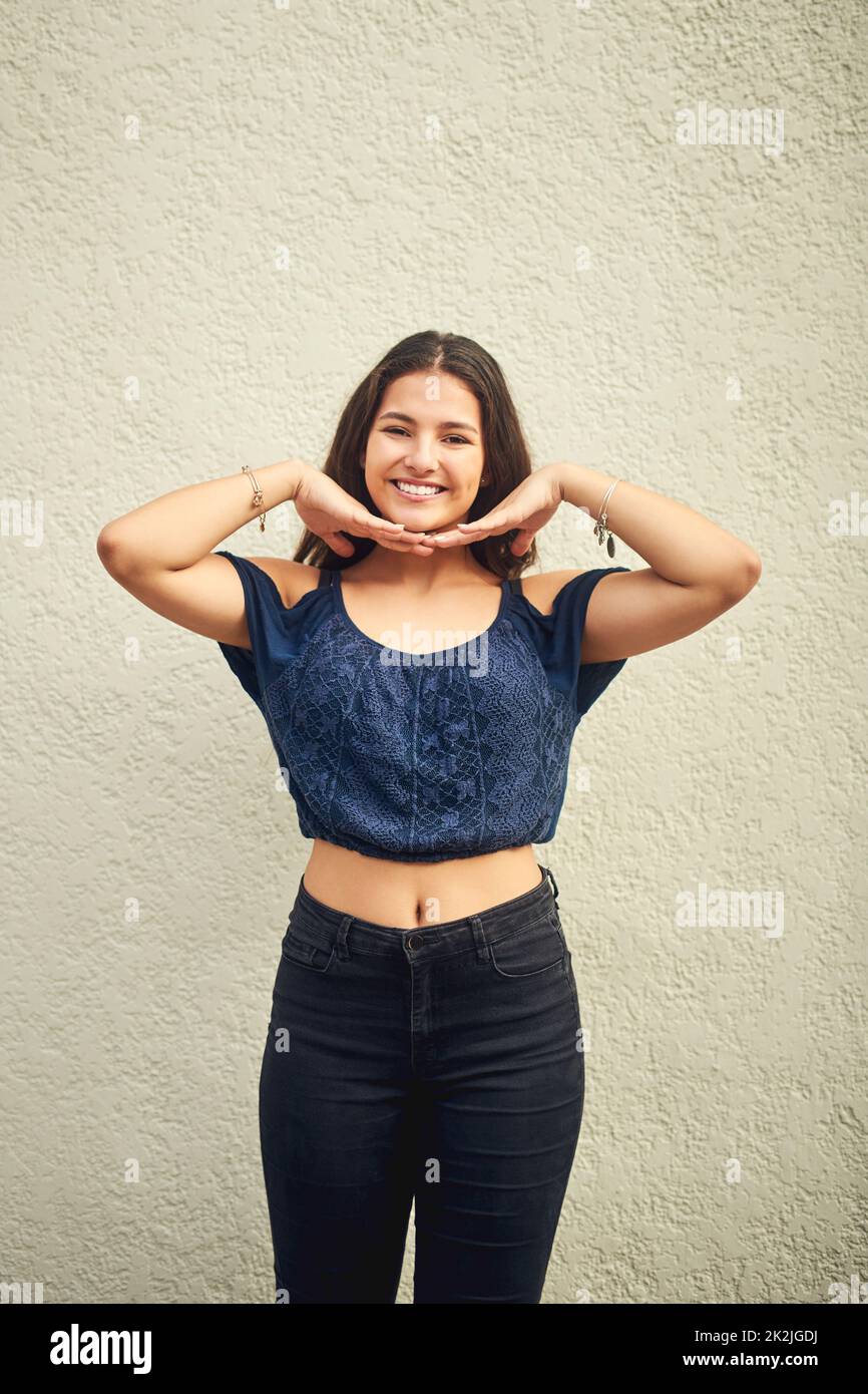 Glück ist etwas, das Sie für sich selbst schaffen müssen. Porträt eines glücklichen Teenagers, das draußen vor einer Wand posiert. Stockfoto