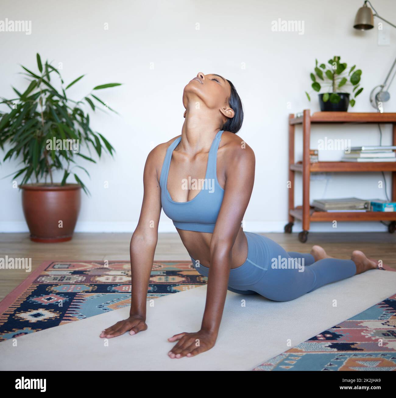 Eine Yoga-Sitzung ist genau das, was Sie brauchen. Aufnahme einer schönen jungen Frau, die zu Hause Yoga praktiziert. Stockfoto