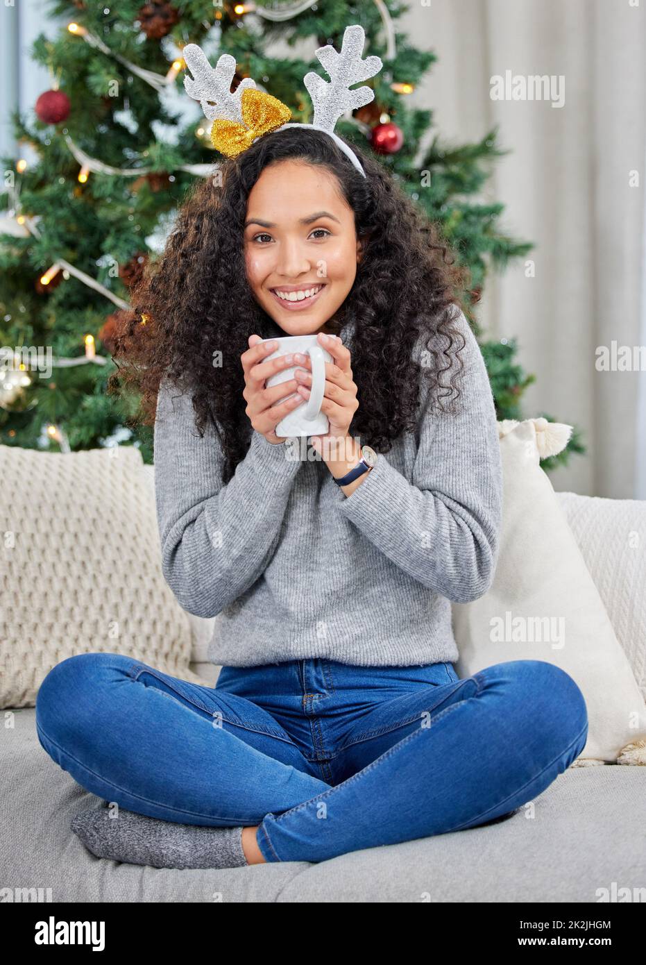 Zu Hause gemütlich machen. Aufnahme einer jungen Frau, die während der Weihnachtszeit zu Hause Kaffee trinkt. Stockfoto