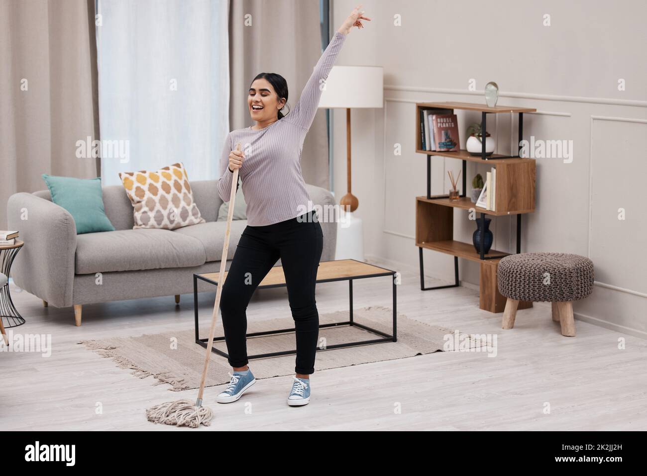 Machen Sie eine Pause, verlieren Sie sich. Aufnahme einer attraktiven jungen Frau, die Spaß hat, während sie ihr Haus putzt. Stockfoto