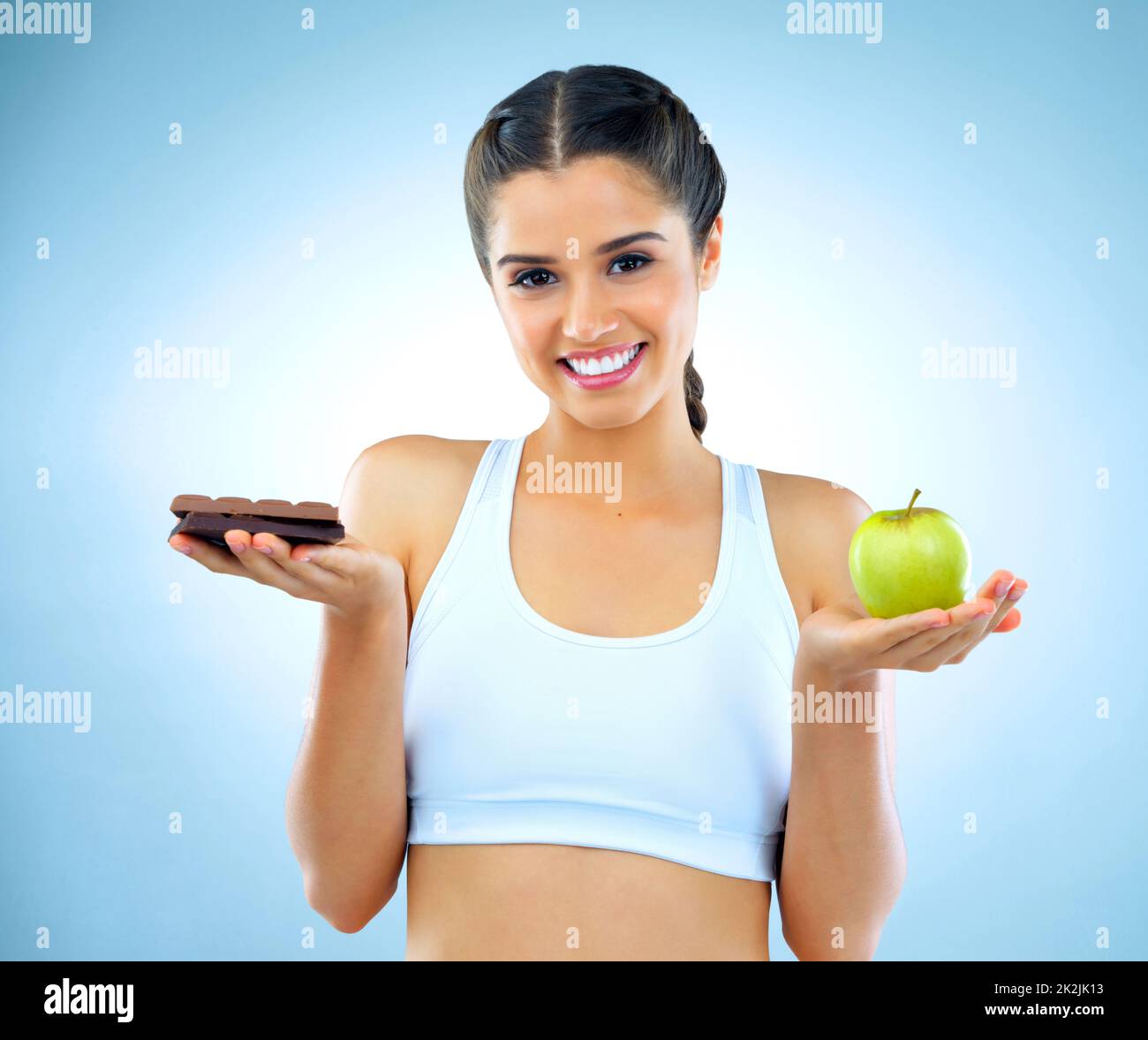 Gesund ist eine Wahl. Studioaufnahme einer Frau, die zwischen gesunden und ungesunden Lebensmitteln entscheidet. Stockfoto