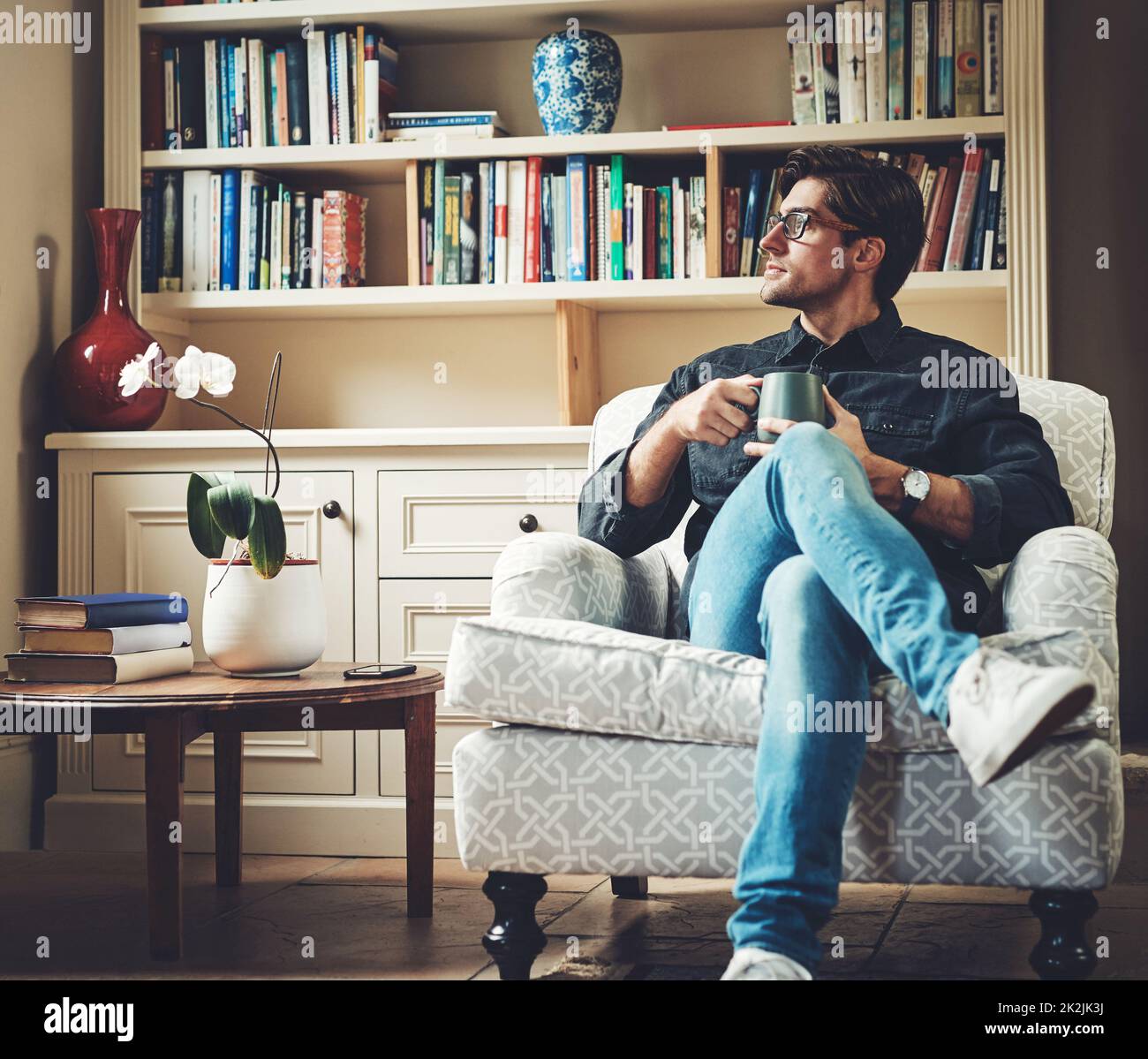 Neue Möglichkeiten ergeben sich jeden neuen Tag. Aufnahme eines hübschen jungen Geschäftsmannes, der Kaffee trinkt, während er zu Hause auf einer Couch in seinem Büro sitzt. Stockfoto