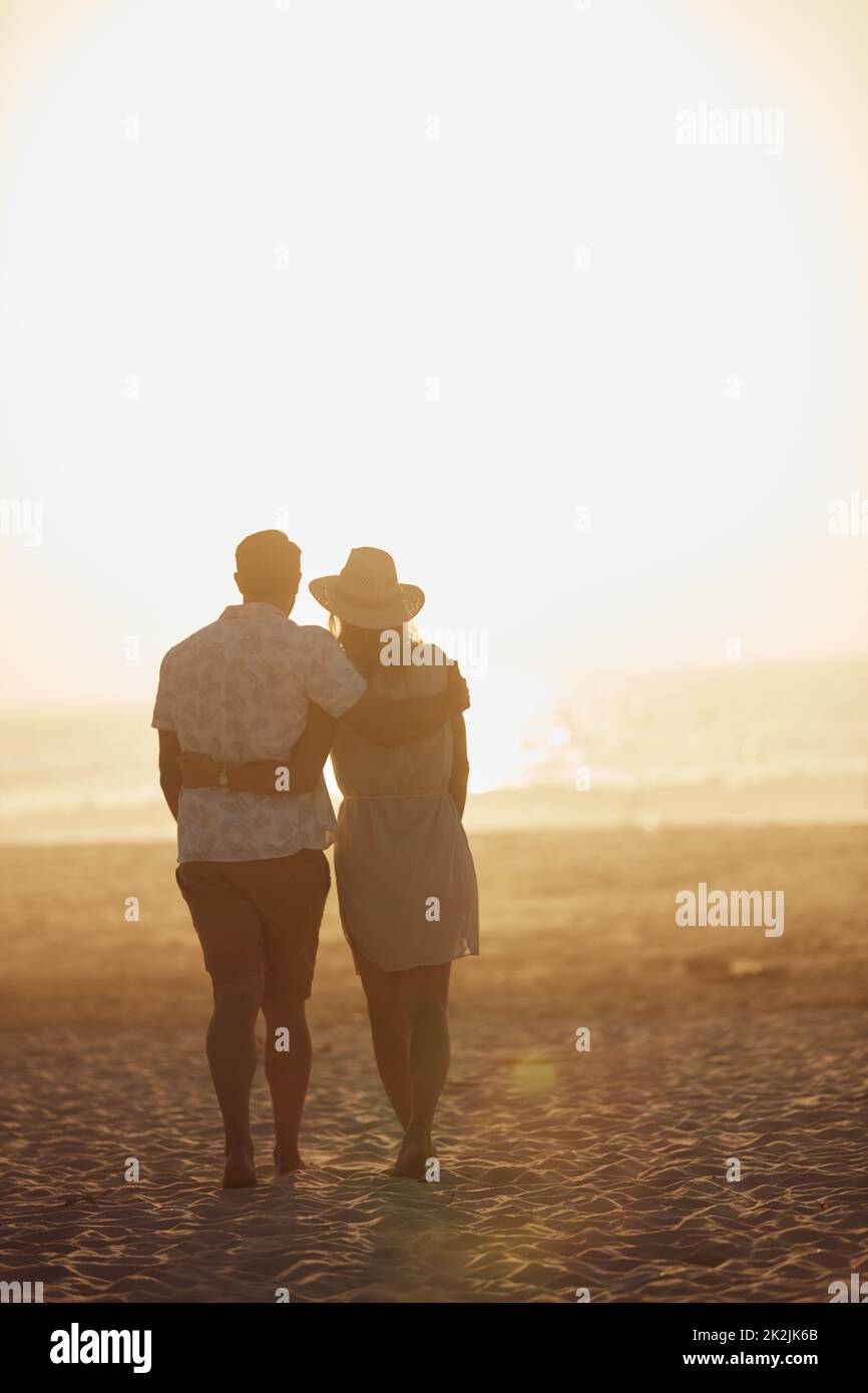 Die meisten Liebesgeschichten beginnen, wenn die Sonne untergeht. Rückansicht eines reiferen Paares, das eine gute Zeit am Strand verbringt. Stockfoto