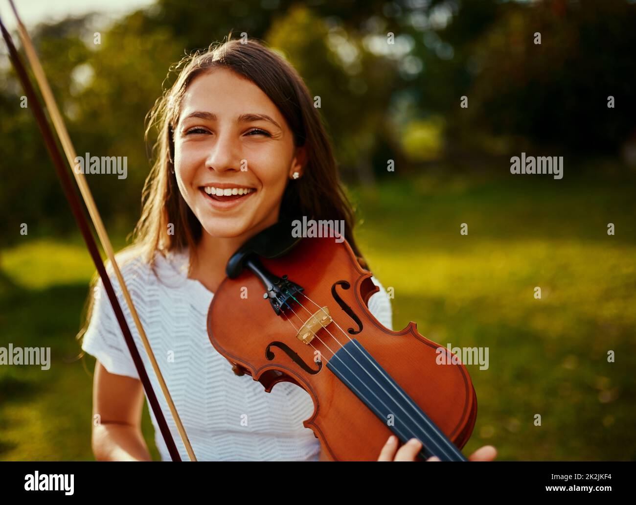 In der Natur zu üben inspiriert sie noch mehr. Ausgeschnittene Aufnahme eines jungen Mädchens, das im Freien eine Geige spielt. Stockfoto