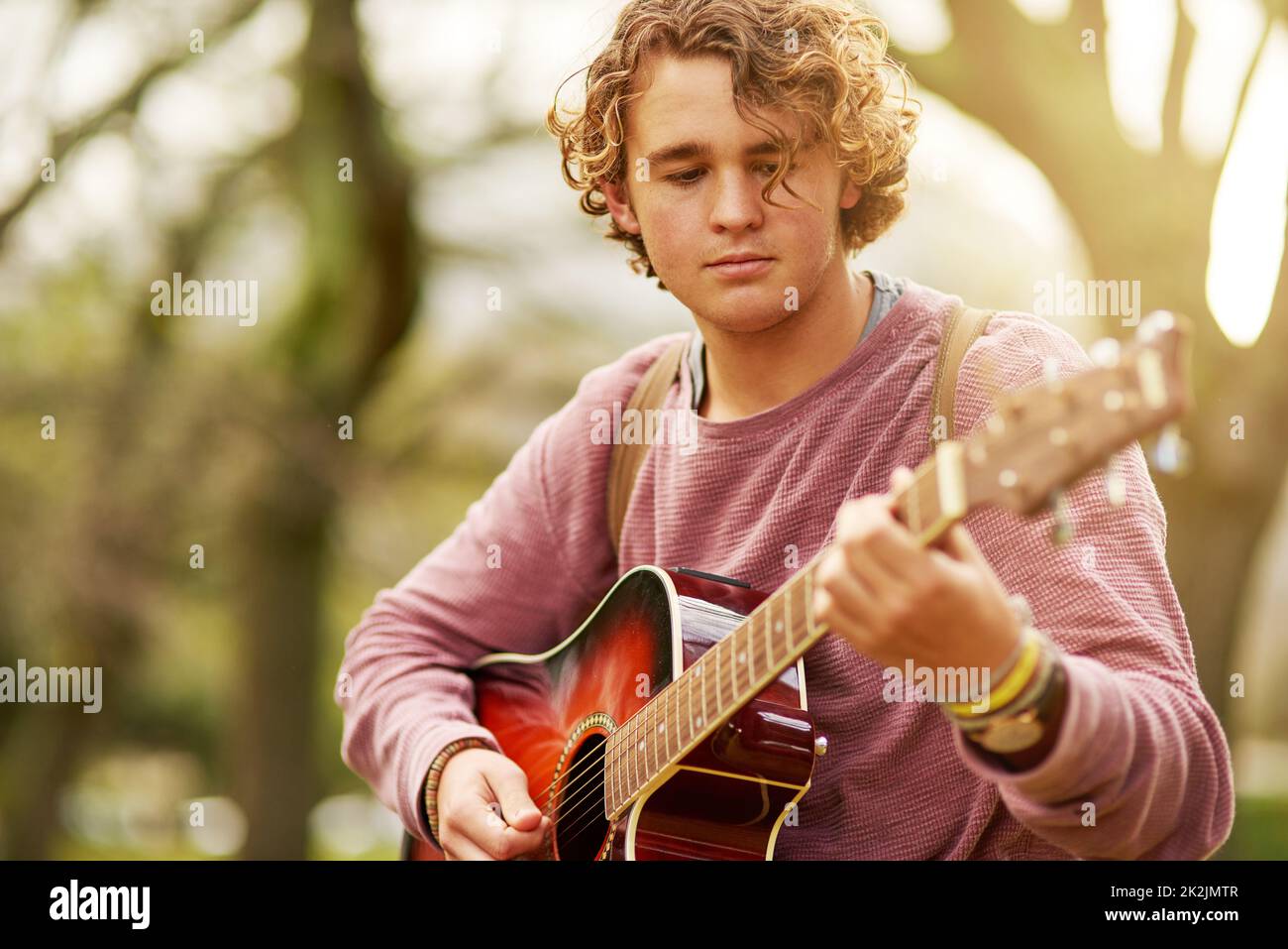 Hes hat die Musik in sich. Aufnahme eines jungen Mannes, der draußen Gitarre spielt. Stockfoto