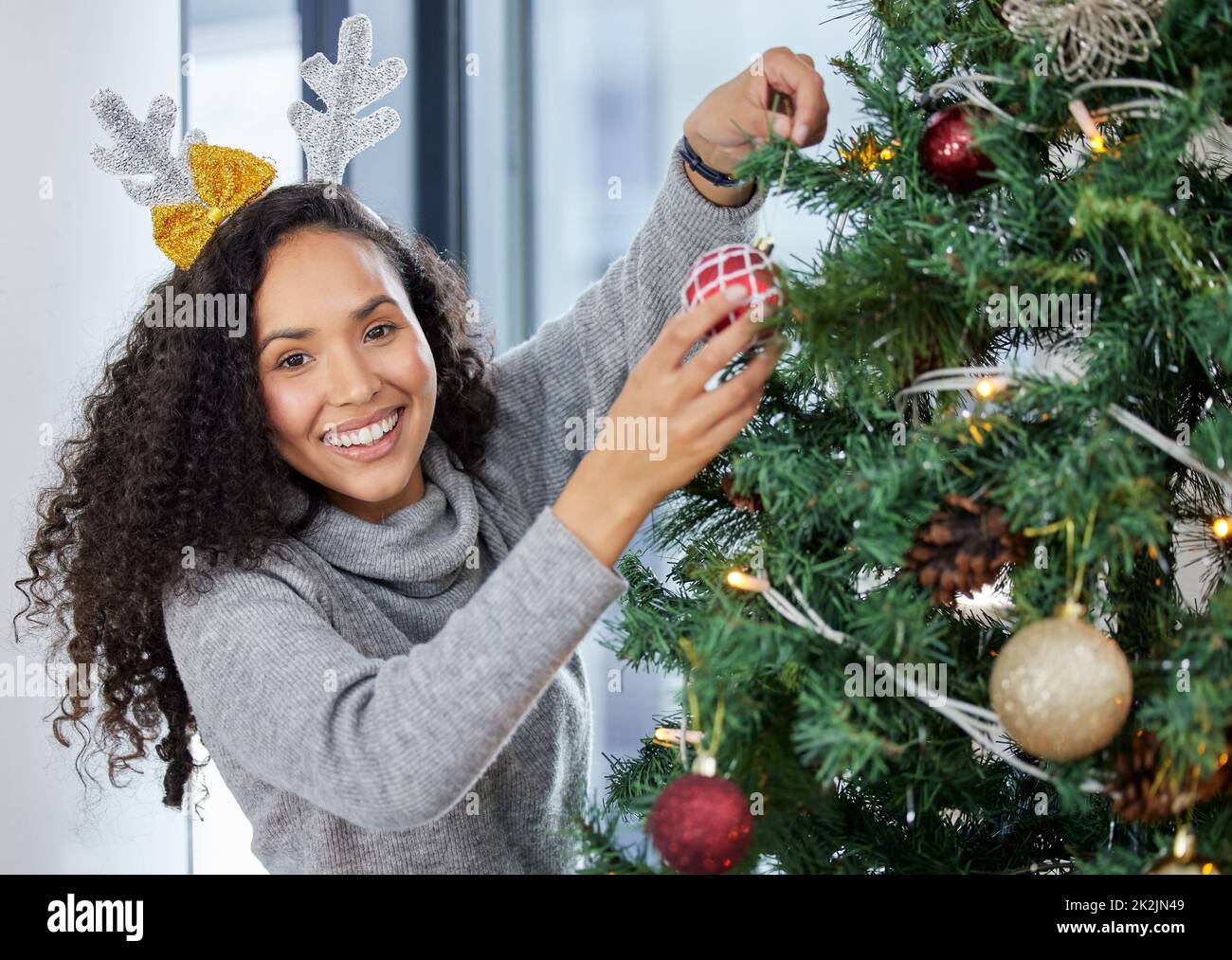 Das Dekorieren ist mein Lieblingsteil. Aufnahme einer jungen Frau, die das Weihnachtsfest zu Hause schmückt. Stockfoto