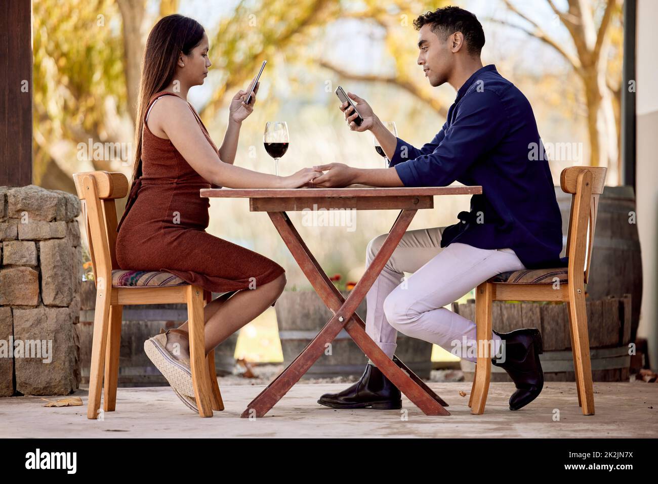 Baby, nur eine Sekunde Ich muss meine Sozialaufnahmen aktualisieren. Aufnahme eines jungen Paares, das Wein auf einem Date auf einer Weinfarm trinkt. Stockfoto